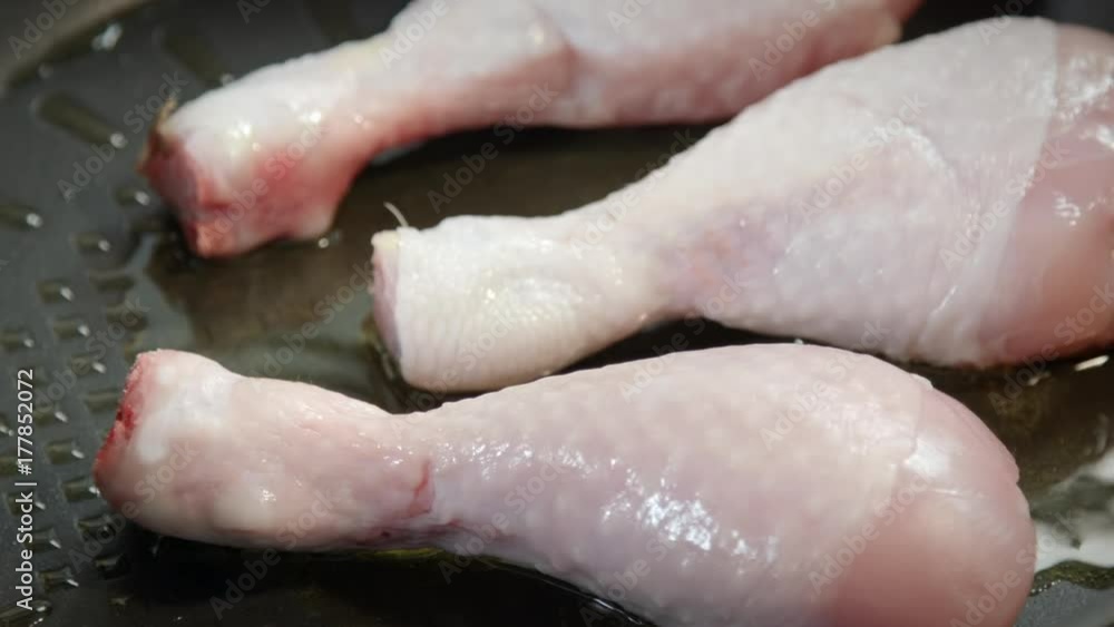 Chef put raw chicken into frying pan close up Chef put raw chicken into frying pan close up