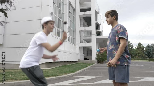 Two teenagers on street practicing new kendama moves