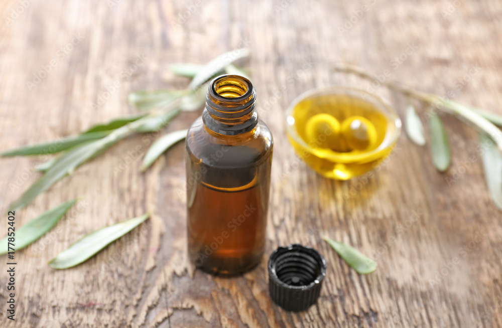 Brown bottle and glass bowl with olive oil on wooden table