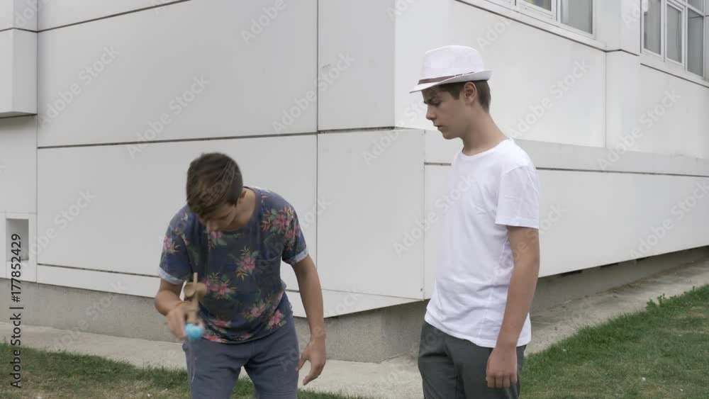Two boys playing with one kendama outdoor Two boys playing with one kendama outdoor
