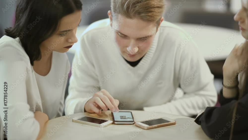 Three friends looks on the screen of smartphone Three friends looks on the screen of smartphone