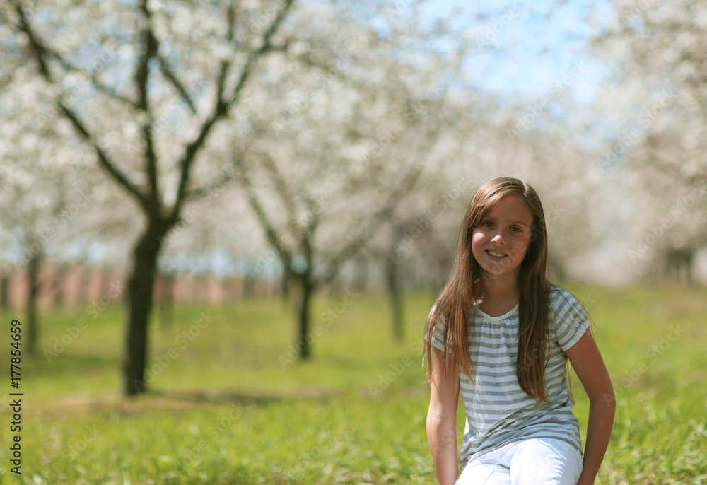 Girl Sitting In An Apple Orchard On A Bright Spring Day Girl Sitting In An Apple Orchard On A Bright Spring Day