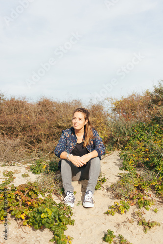 Young woman relaxing in the dunes to enjoy the sunshine. photo