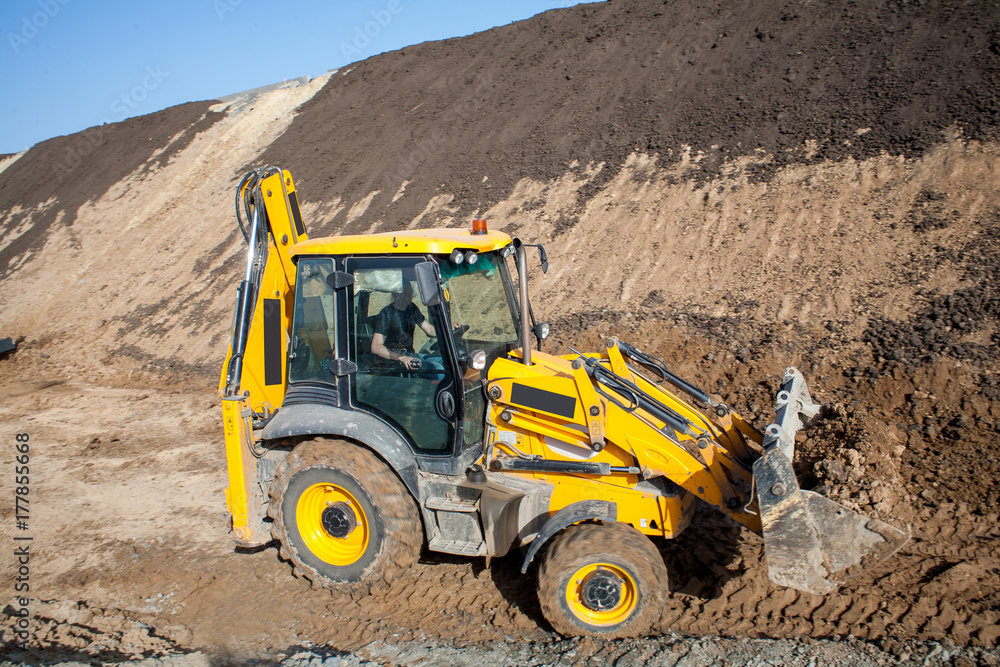 Tractor loader backhoe digger loader on a construction site with blue sky Tractor loader backhoe digger loader on a construction site with blue sky