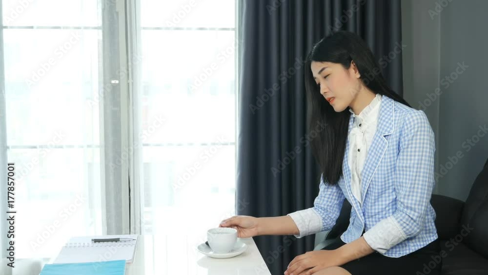 Beautiful young business woman smile sitting on a sofa and having a coffee break in office Beautiful young business woman smile sitting on a sofa and having a coffee break in office