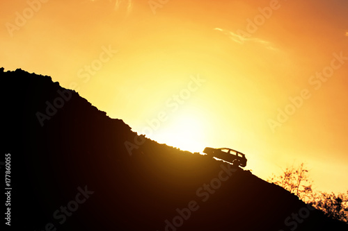 Fototapeta Toy car drive uphill and light of sunrise. Concept effort