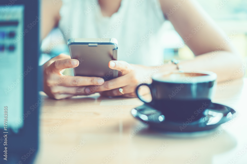 Women's hands holding smartphone with coffee on notebook place Women's hands holding smartphone with coffee on notebook place
