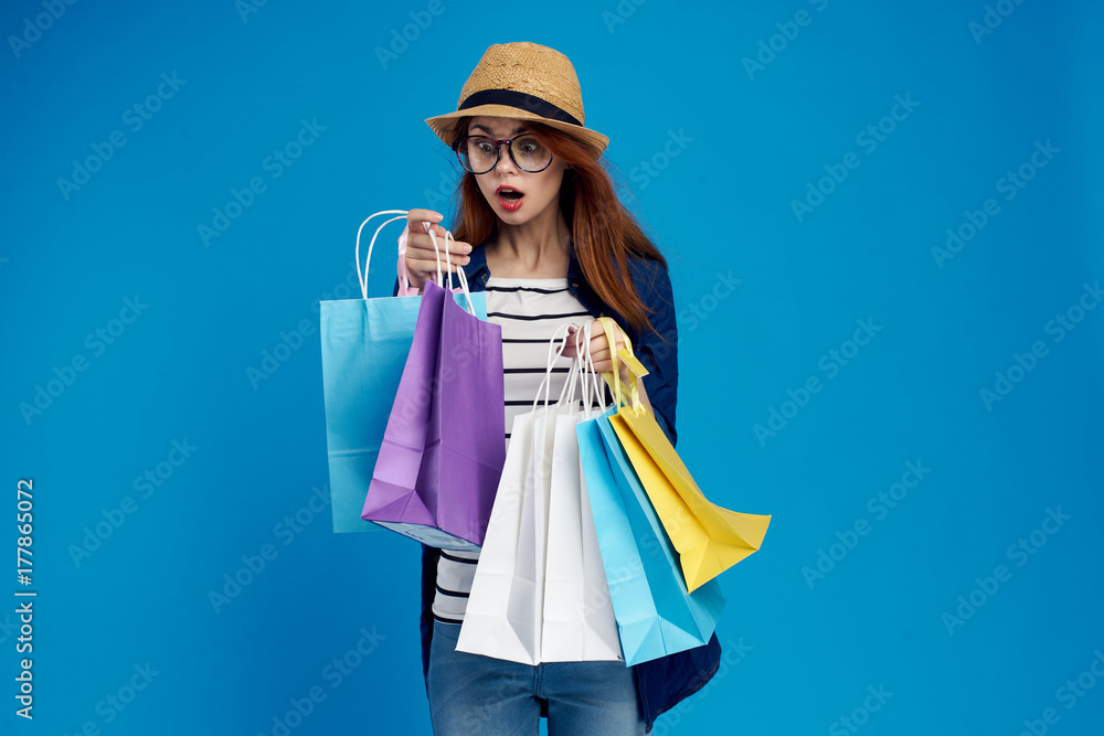 the girl looks at her purchases with a surprised look on a blue background