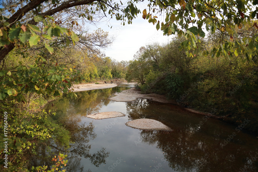Horizontal landscape of a river in Mark Twain Forest, Southwest, Missouri, in the Fall featuring sky, trees, fall leaves, reflections, and sand bars