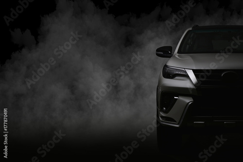 Studio shot of white car isolated on black background with shadow and smoke fog.