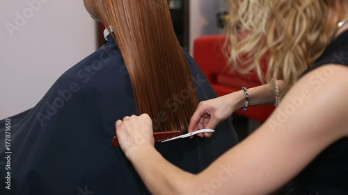 Female hairdresser making a haircut for redhead female client