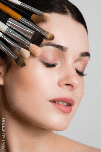 Beautiful woman with makeup brushes near her face