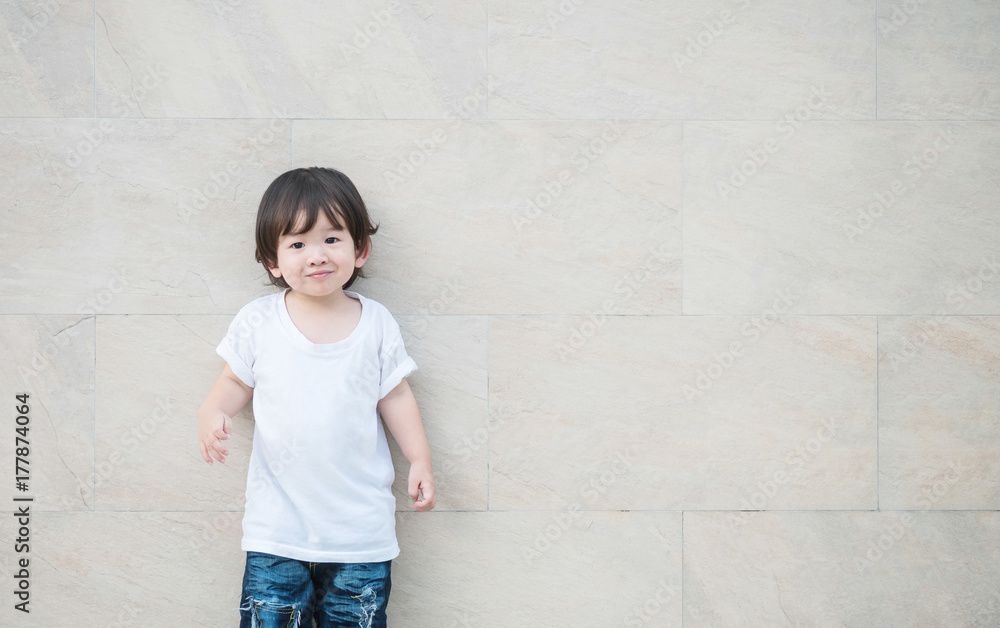 Closeup happy asian kid with smile face on marble stone wall textured background with copy space Closeup happy asian kid with smile face on marble stone wall textured background with copy space