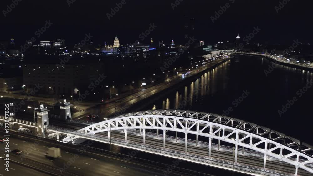 Aerial view of Luzhniki Metro Bridge, also known as Metromost, heavy traffic at night.Moscow river and city skyline during sunset. Big city life concept. Aerial view of Luzhniki Metro Bridge, also known as Metromost, heavy traffic at night.Moscow river and city skyline during sunset. Big city life concept.