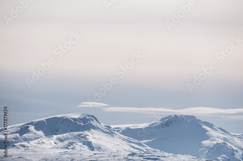 Snow capped mountain peak and blue sky with white clouds in winter, winter landscape in Iceland