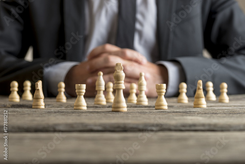 Man wearing suit sitting in front of white chess