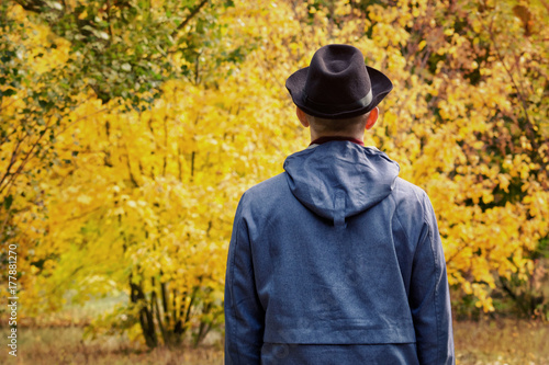 Man in a black hat is standing in the forest. Autumn concept. Back view