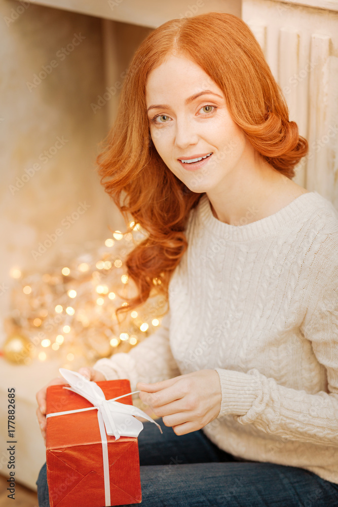 Cheerful ginger woman opening present at home Cheerful ginger woman opening present at home