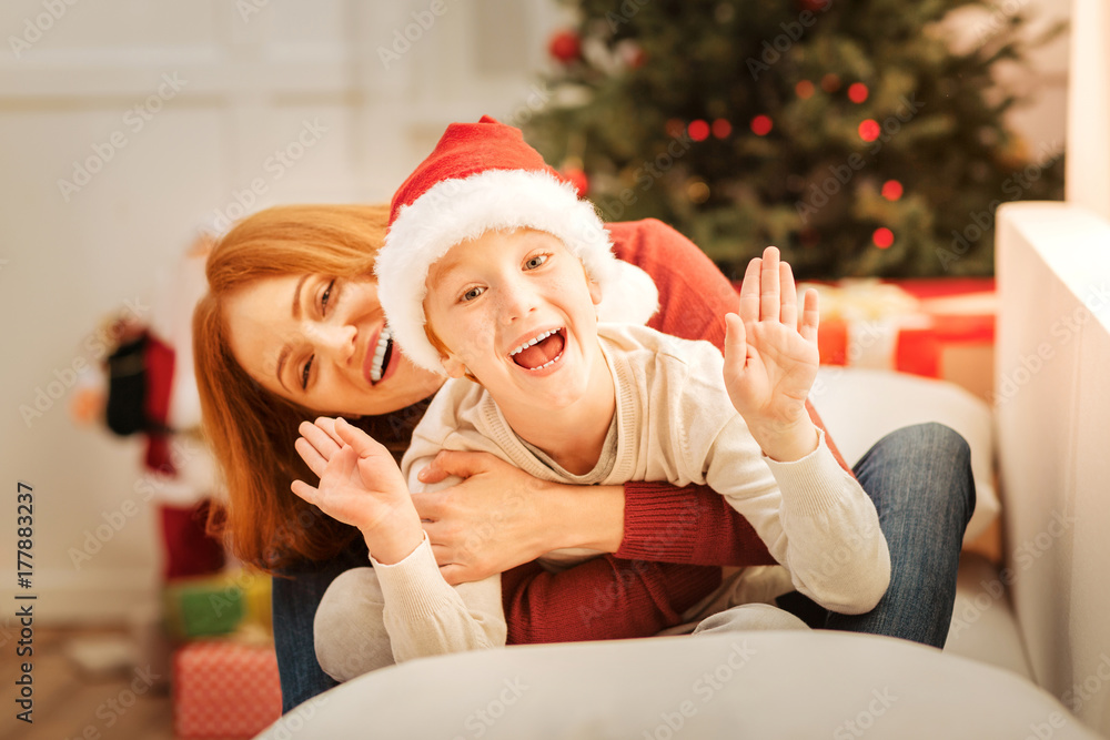 Excited mother and son beaming while embracing on sofa Excited mother and son beaming while embracing on sofa