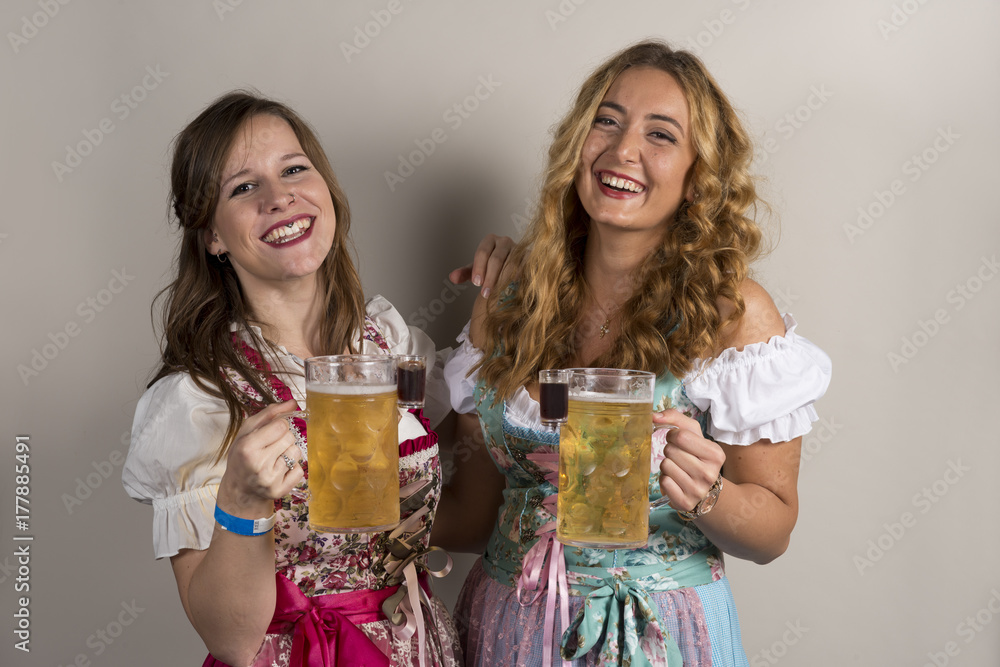 Two Happy Ladies Wearing Dirndls with Beer and Shots Two Happy Ladies Wearing Dirndls with Beer and Shots