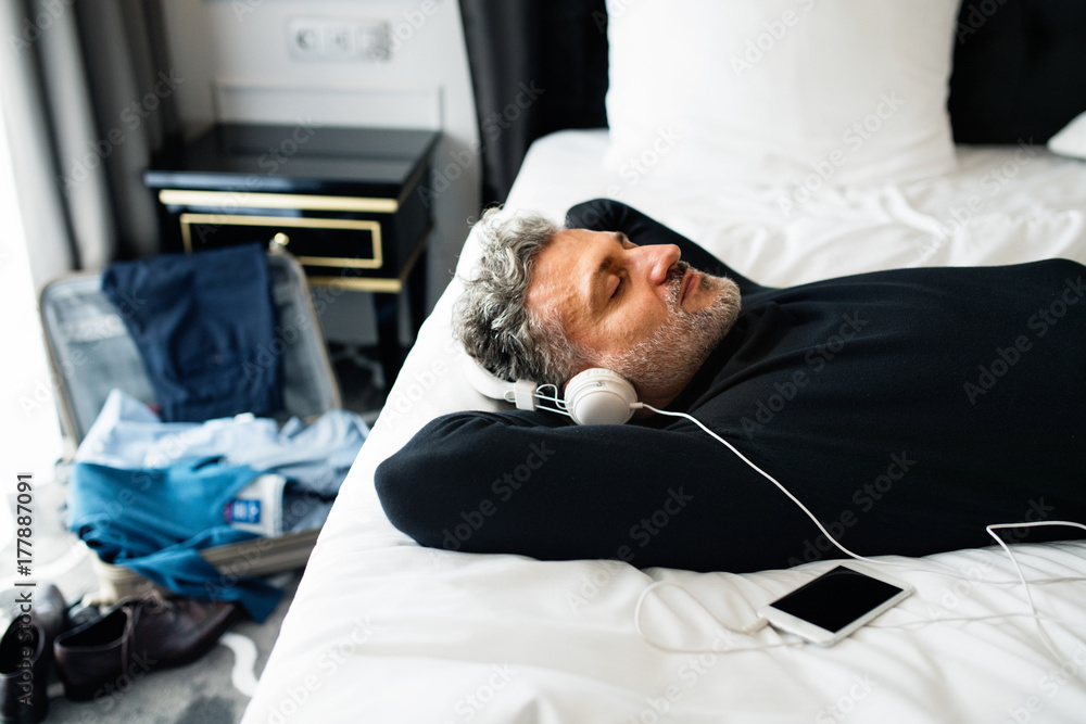 Obraz premium Mature businessman with smartphone in a hotel room.