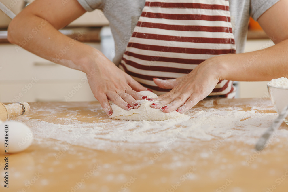 A young beautiful happy woman sitting at a table with flour, kneading dough and going to prepare a Christmas cakes in the kitchen. Cooking home. Prepare food close up.