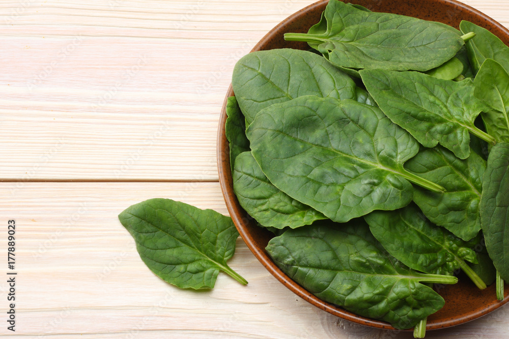 spinach leaves in bowl on white wooden table top view spinach leaves in bowl on white wooden table top view