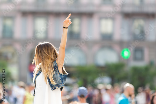 Pretty teenager outdoor, pointing up with her hands. Defocused background with copy space.