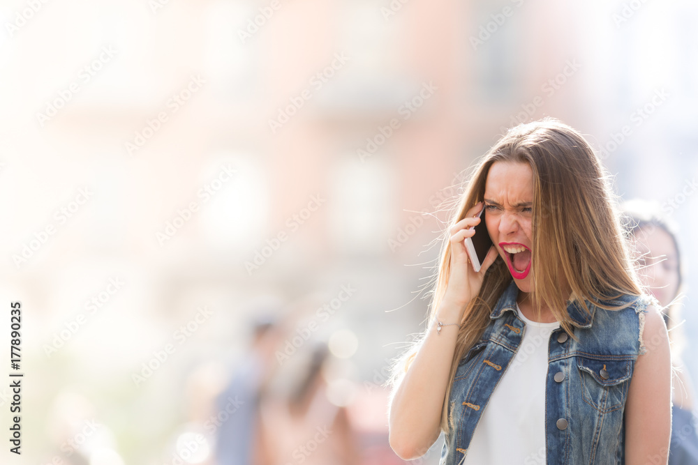 Angry and upset teenager screaming at the mobile telephone Angry and upset teenager screaming at the mobile telephone