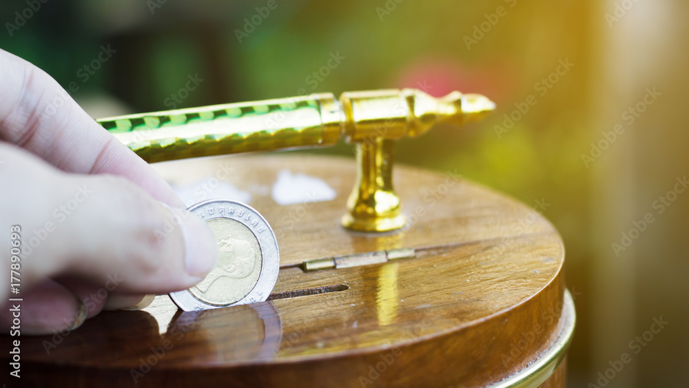 Obraz premium Hand holding coin drops into a wooden piggy bank. Saving coin concept. Conceptual saving money for business or life in future. Concept saving money background for web banner. Investment money Concept.
