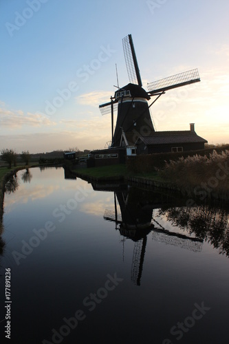 Dutch windmill in evening sun reflects in water