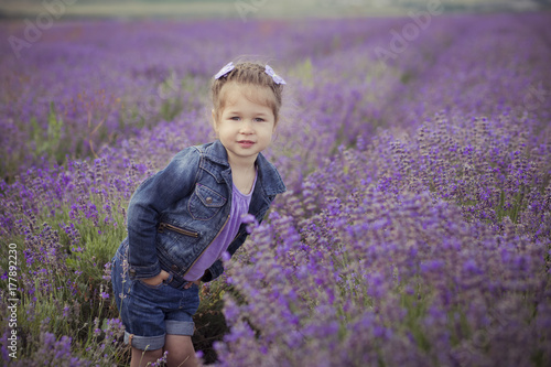 Beautifull cute blond Young beauty girl in blue jeans and purple shirt posing to camera with cosy smile face.Wellbeing time spending in village fields of lavender in august France Provence photo