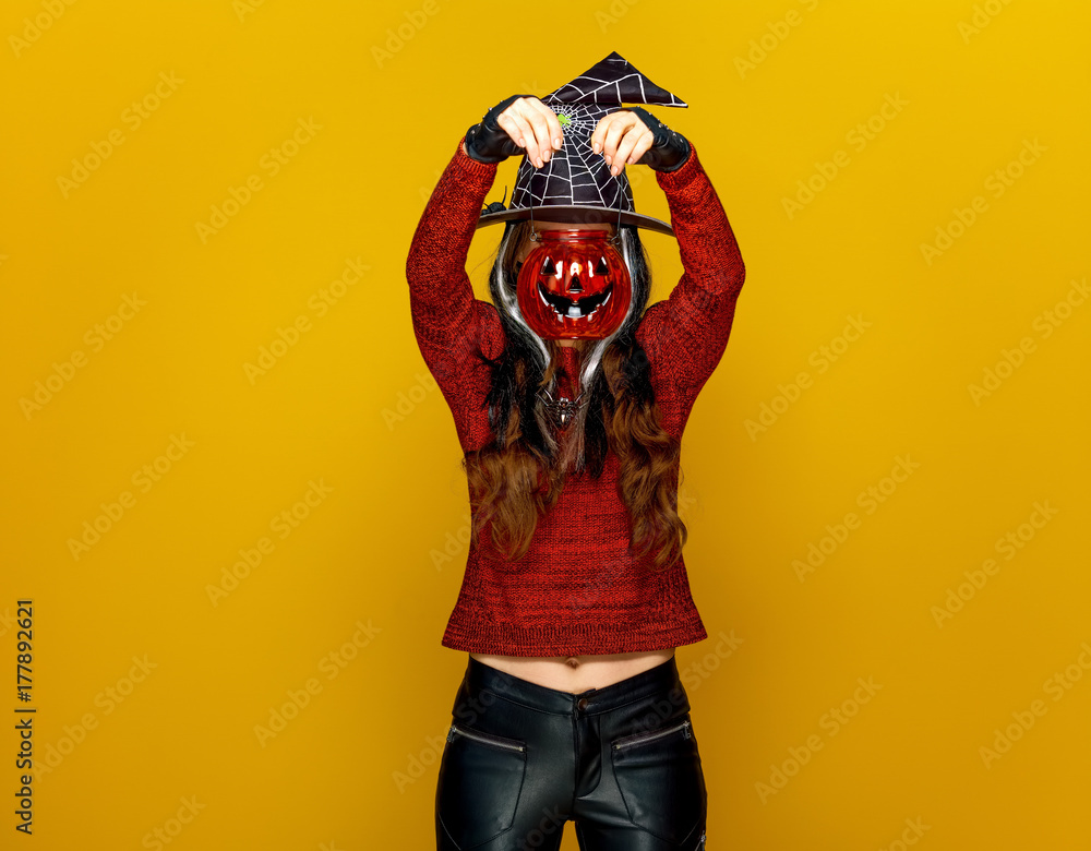 young woman holding jack-o-lantern in front of face young woman holding jack-o-lantern in front of face