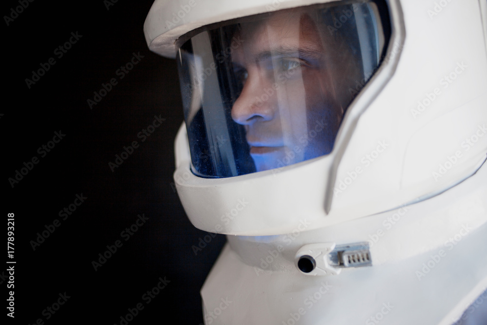 Fototapeta premium Astronaut in a helmet looks down. Fantastic space suit. Exploration of outer space.