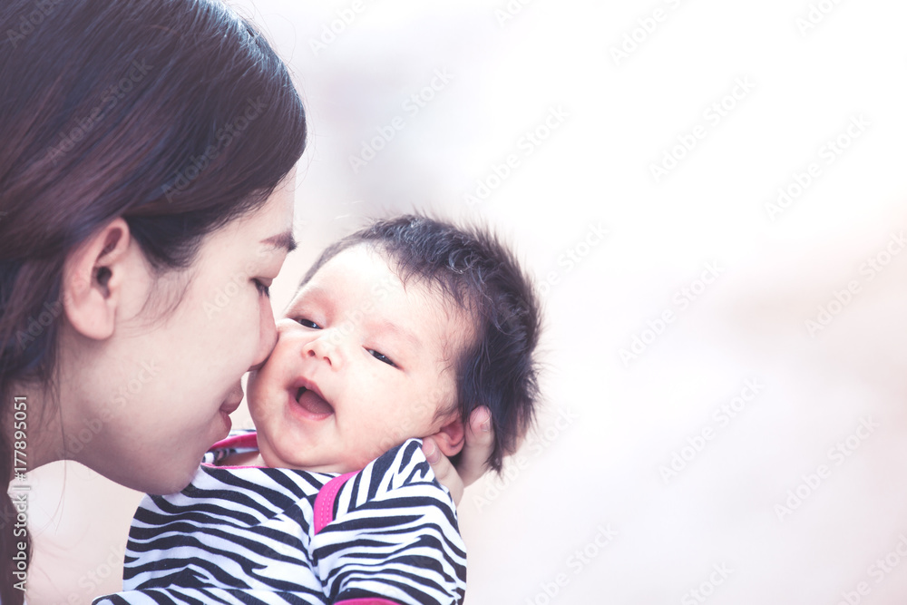 Young asian mother hugging and kissing her newborn baby girl with love in vintage color tone Young asian mother hugging and kissing her newborn baby girl with love in vintage color tone
