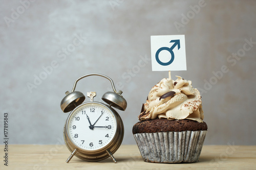 Cupcake with cream and alarm clock
