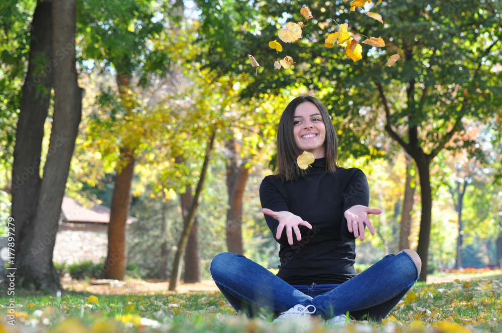 Happy woman enjoy in autumn park. Smiling girl throwing leaves
