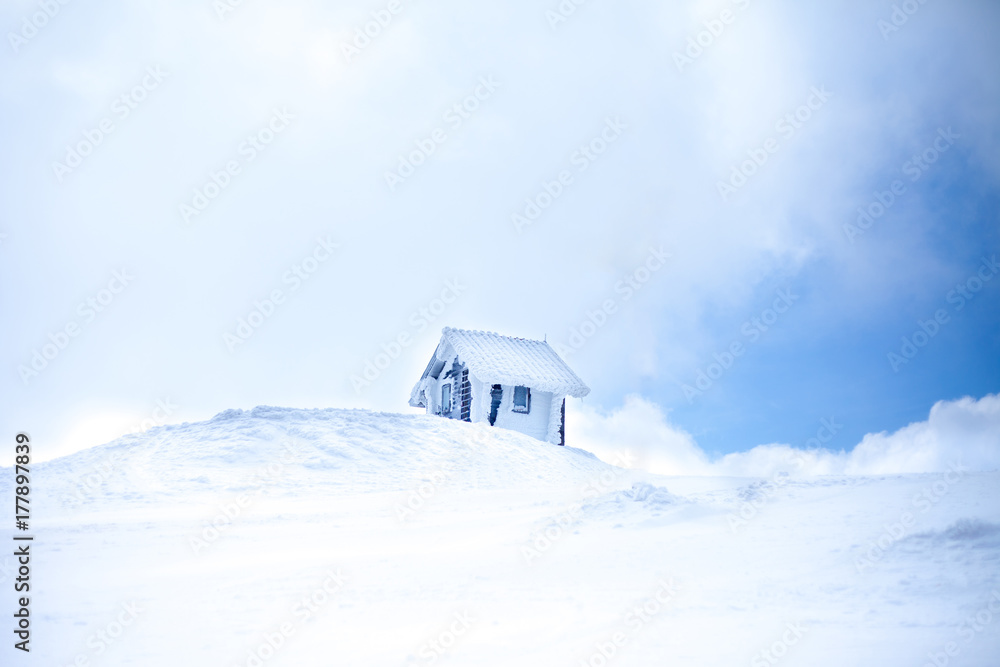 Small house on the top of the mountain covered with snow. 