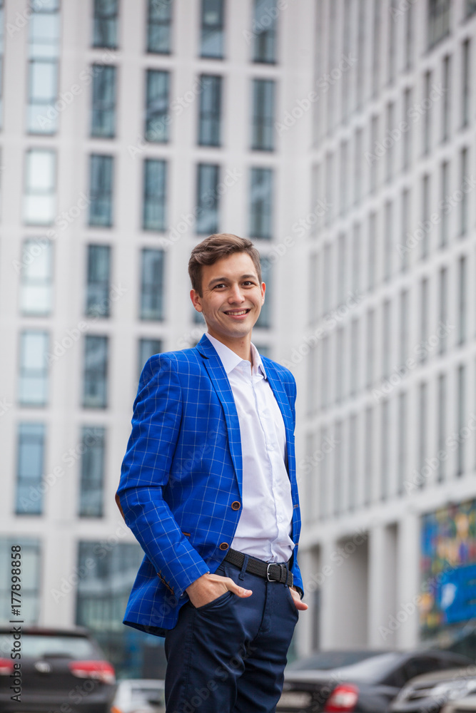 guy in business style clothes on the background of a tall building. A blue jacket. Stylish guy guy in business style clothes on the background of a tall building. A blue jacket. Stylish guy