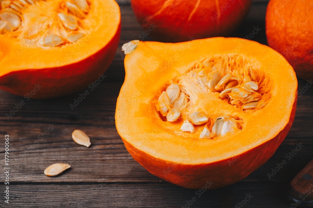raw pumpkin slices with seeds on a wooden background.