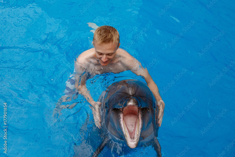 Fototapeta premium happy man swim with dolphin in dolphinarium