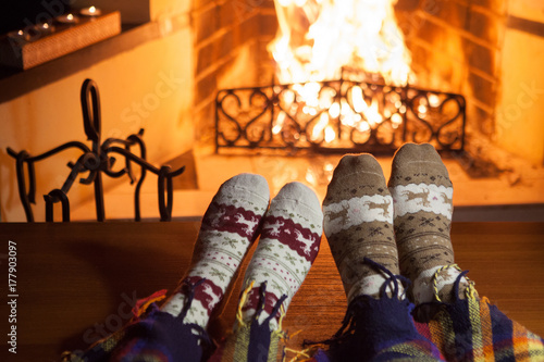 Man and woman in warm socks near fireplace. Happy couple.