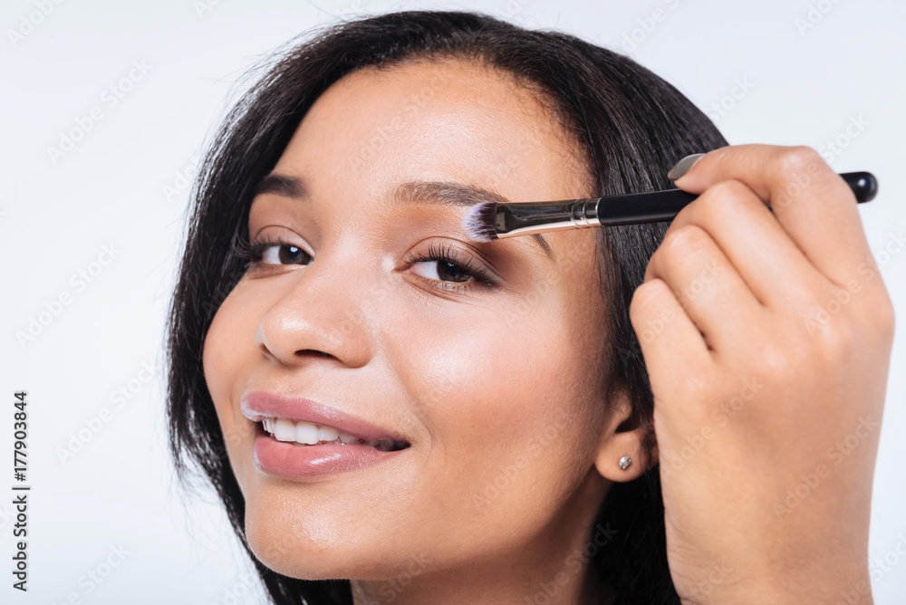 Close up of smiling woman applying eyeshadows