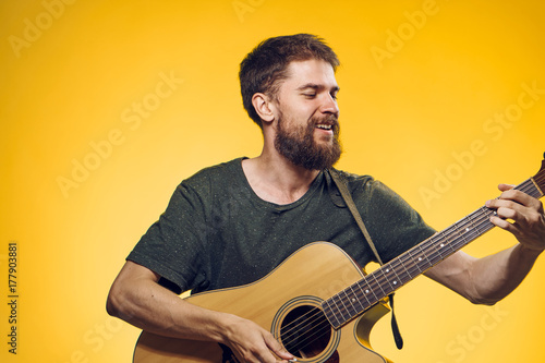 man on a yellow background playing the guitar