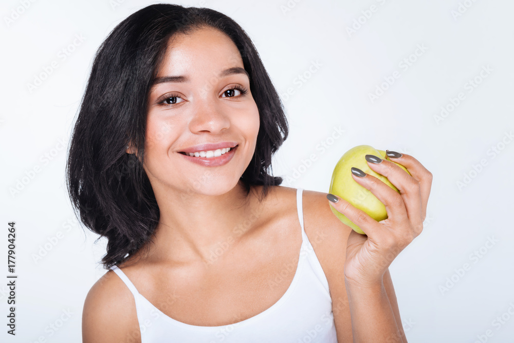 Smiling dark-haired woman holding an apple Smiling dark-haired woman holding an apple