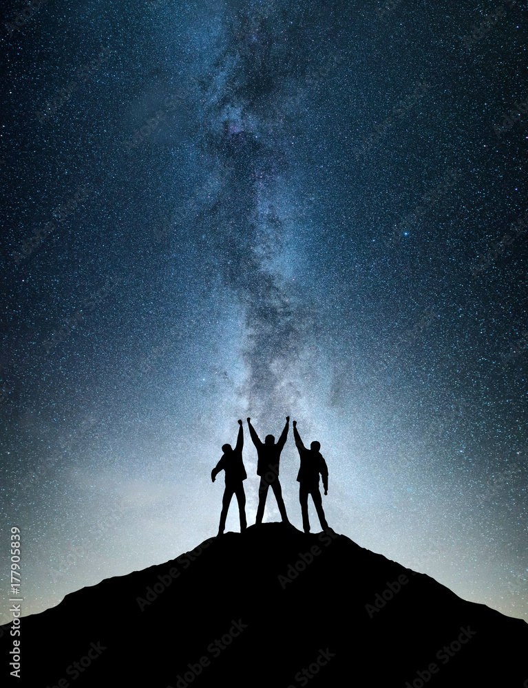 Silhouettes of team on mountain peak. Sport and active life concept on the night sky background.