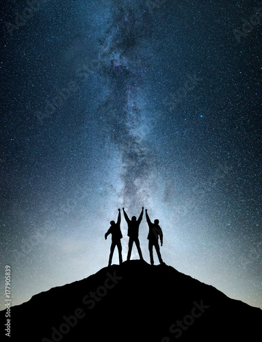 Silhouettes of team on mountain peak. Sport and active life concept on the ni...