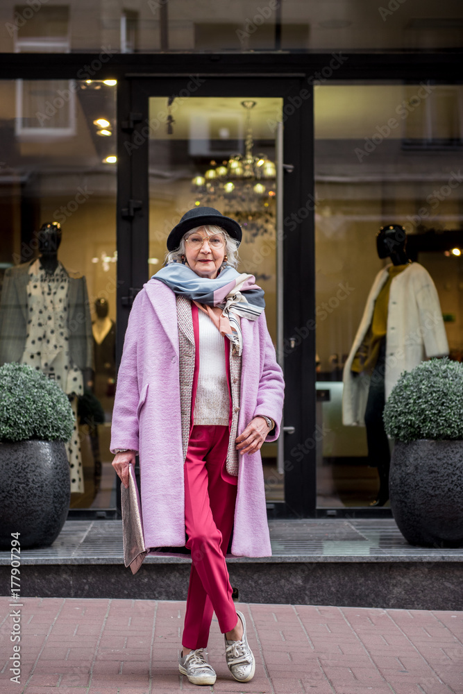 Elegant senior woman standing near boutique on street