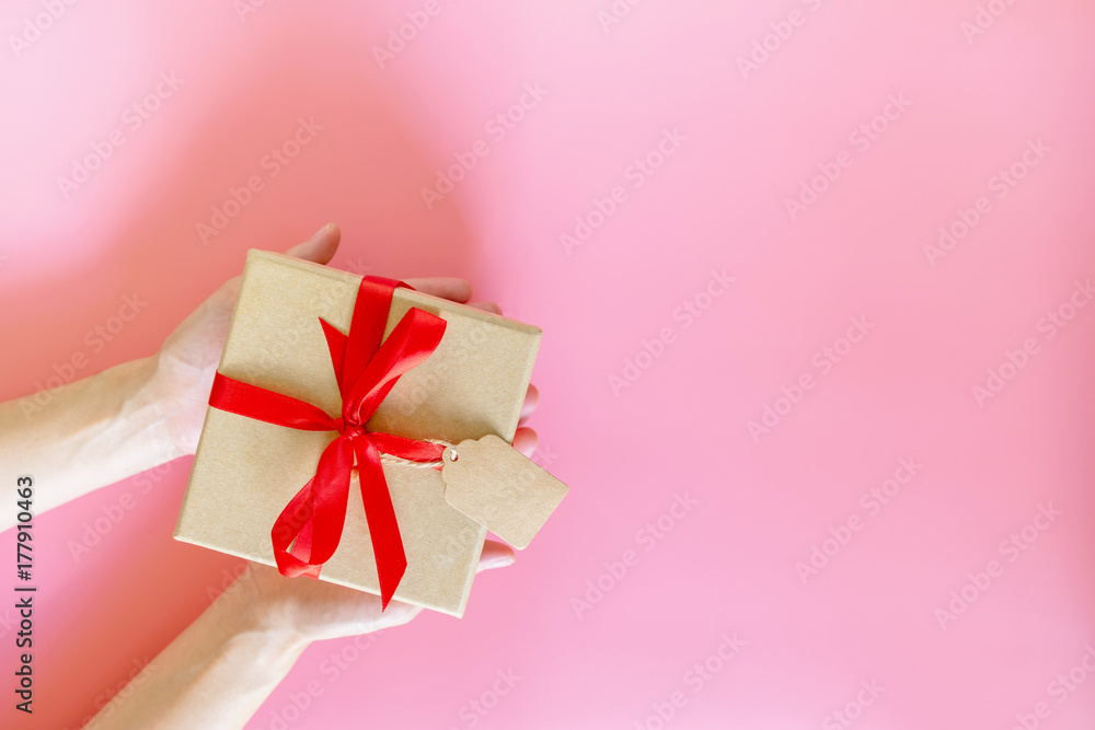 top view hand woman holding brown gift box for new year on pink pastel color with space.
