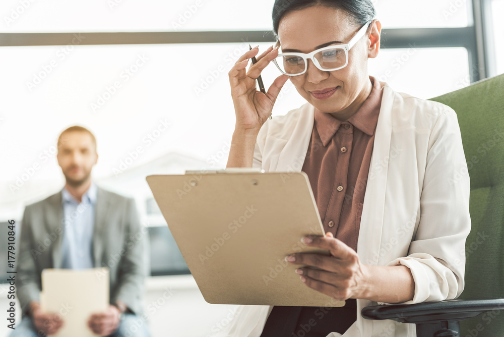 Busy smiling psychotherapist holding papers Busy smiling psychotherapist holding papers